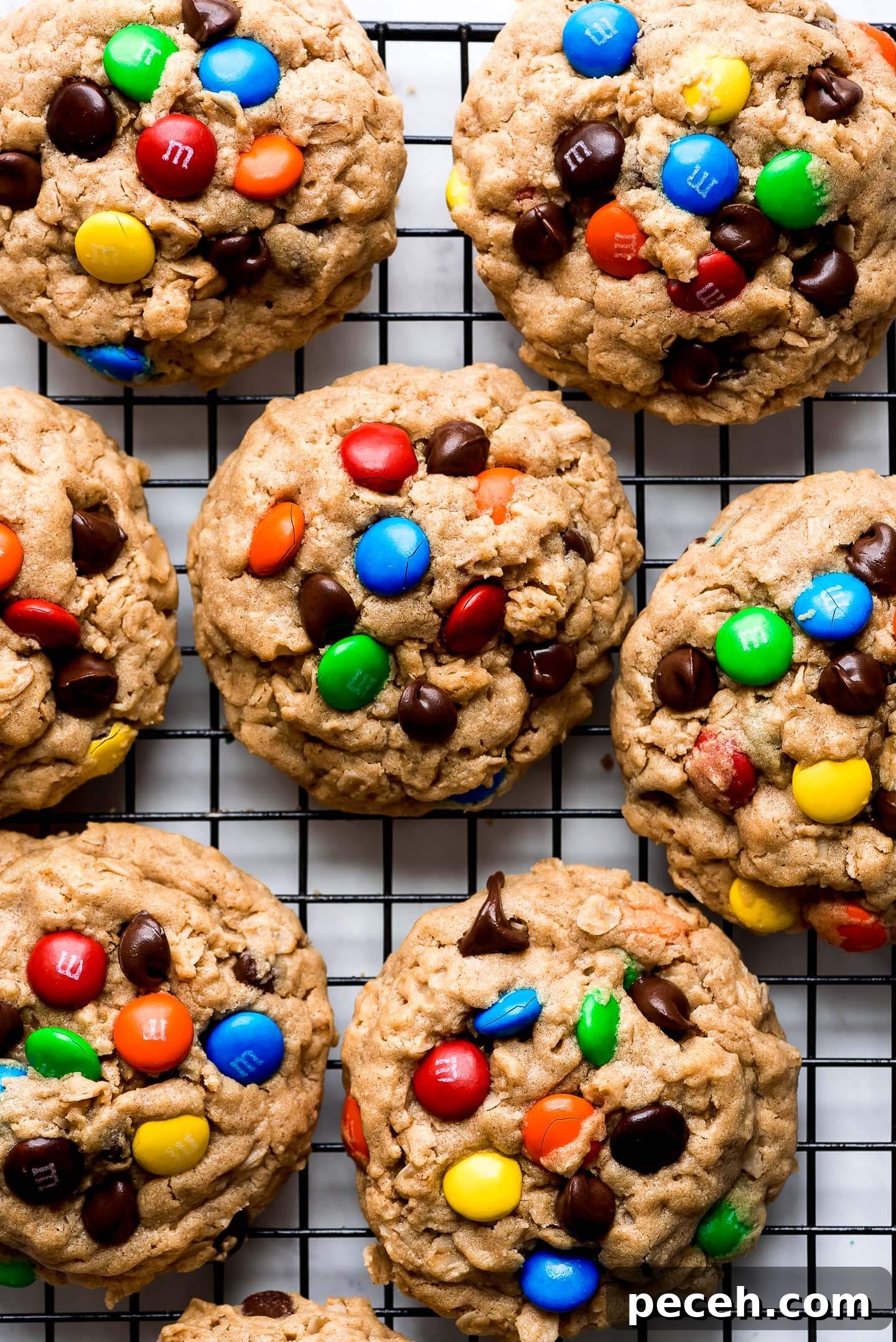 Soft Chewy Monster Cookies Recipe – Loaded Chocolate Chip Cookies 8 Monster Cookies on a cooking rack topped with chocolate chips and colorful M&M's.