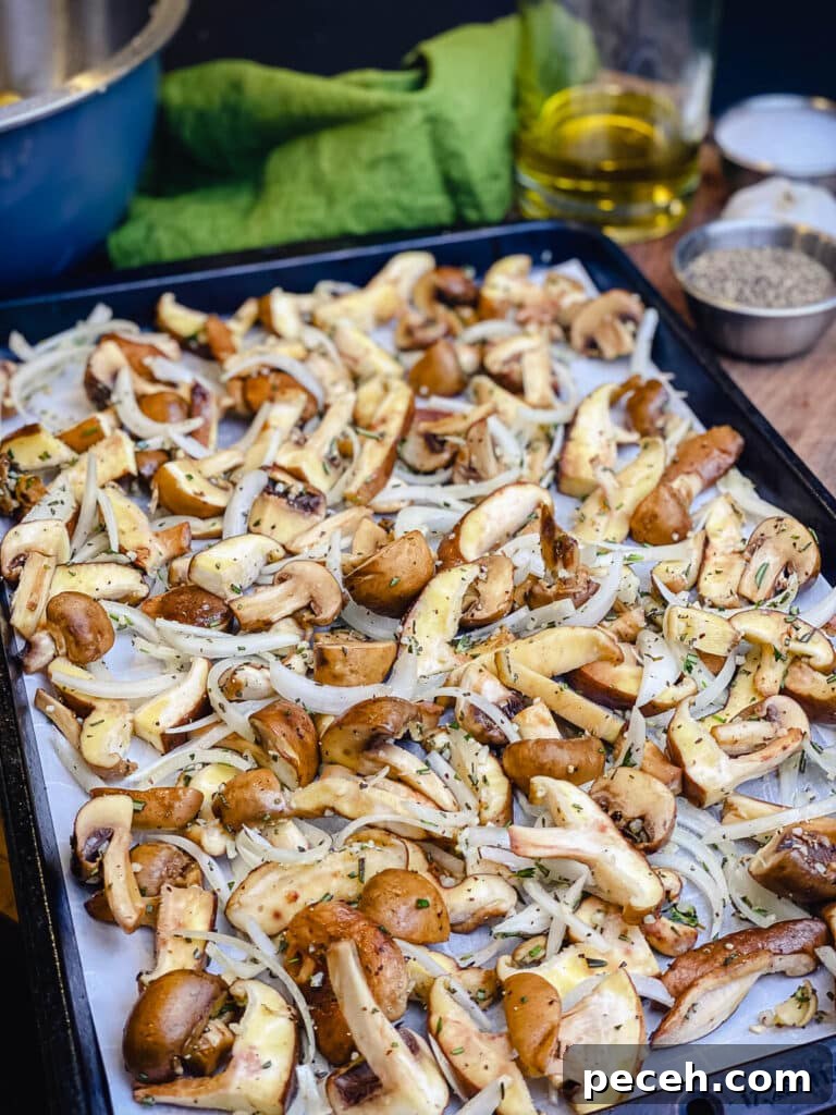 Creamy Chicken and Mushroom Rigatoni Recipe for Weeknights 8 mushrooms and onions on a parchment lined baking sheet