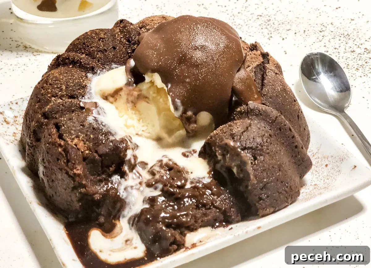A plate with a chocolate molten lava cake that's been broken into. 