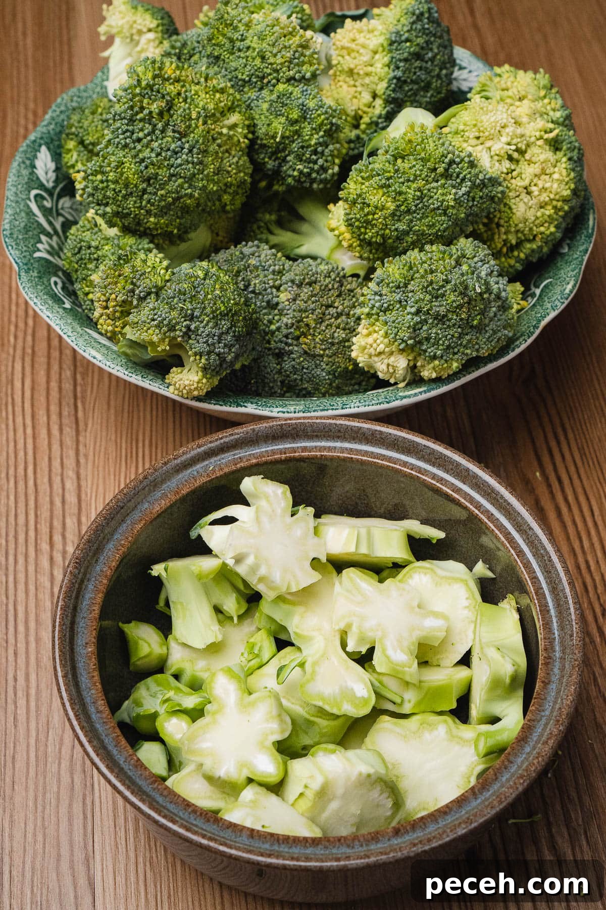 Chopped broccoli stems in a bowl and broccoli florets in another bowl