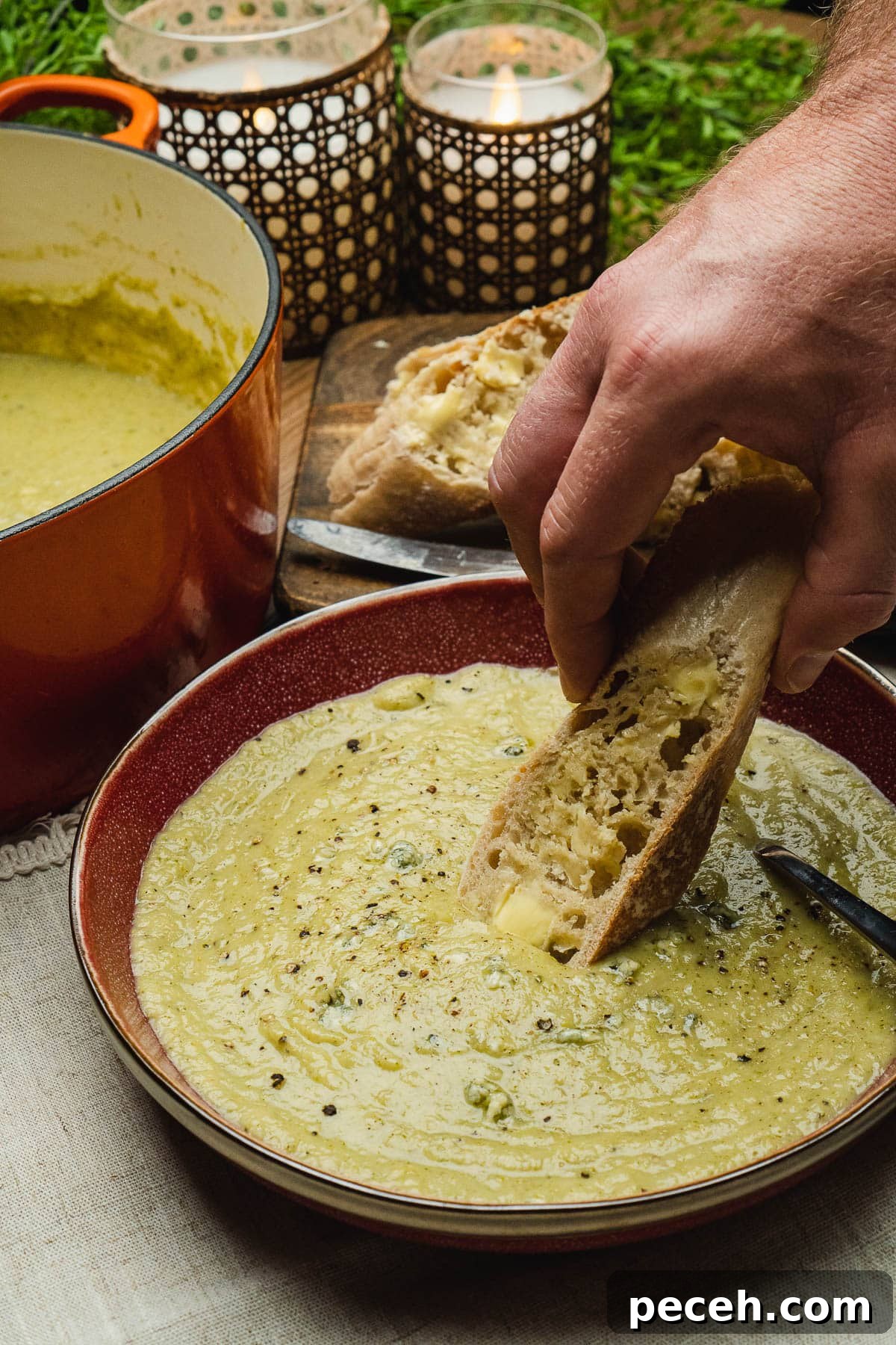 Dipping crusty bread into a bowl of stilton and broccoli soup