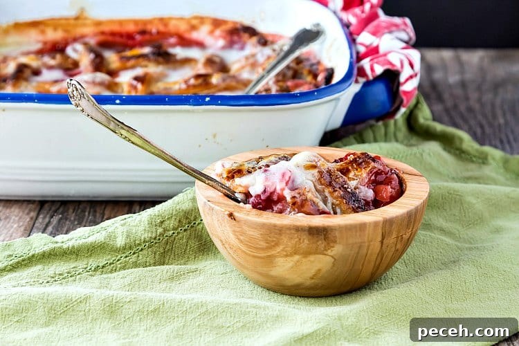 A bowl of cobbler and the baking dish of cobbler in the background.