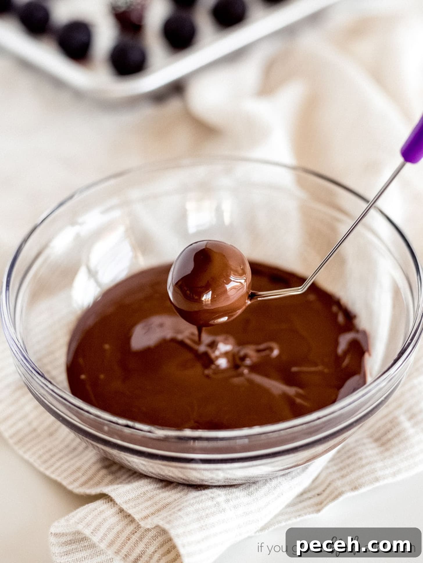 How to Melt Chocolate: Microwave and Stovetop Methods 5 dipping tool holding chocolate covered oreo truffle over bowl of melted chocolate.
