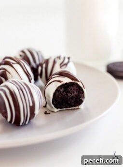white chocolate covered oreo truffle with a bite on a plate with more truffles.