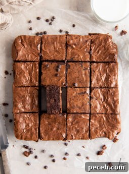 brownie on its side next to more brownies cut into squares on parchment paper.