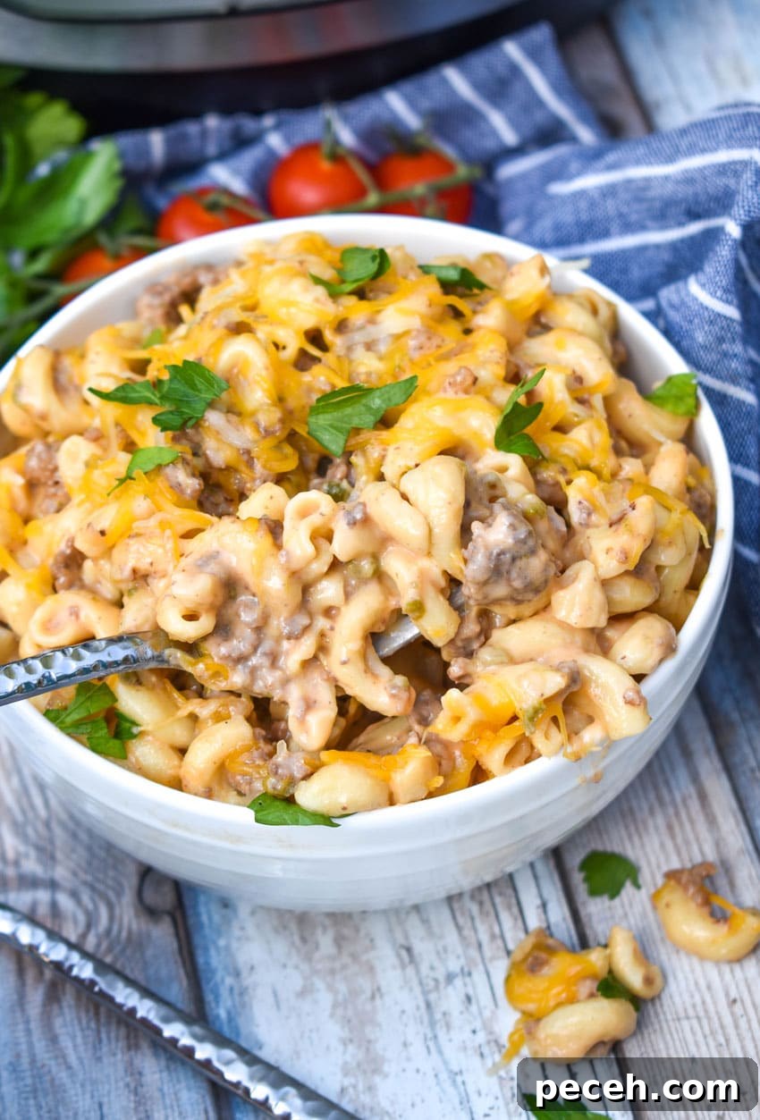 Instant Pot Cheeseburger Macaroni Skillet Recipe 6 a silver fork stuck in a white bowl filled with instant pot cheeseburger pasta