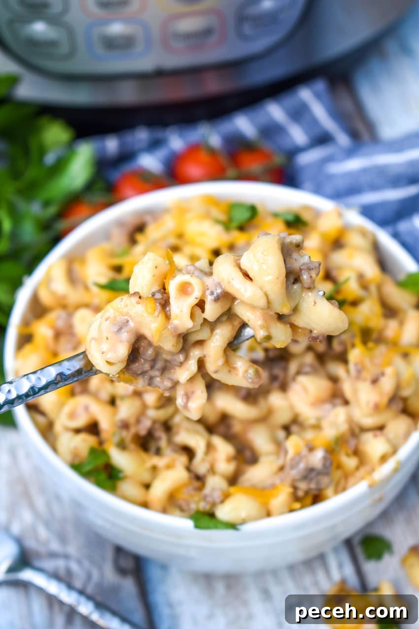 Instant Pot Cheeseburger Macaroni Skillet Recipe 7 a silver fork stuck in a white bowl filled with instant pot cheeseburger pasta
