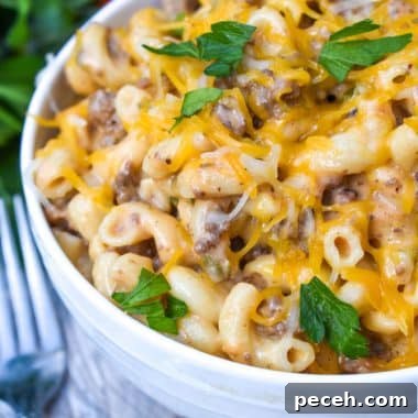 instant pot cheeseburger macaroni in a white bowl with two silver forks on the side