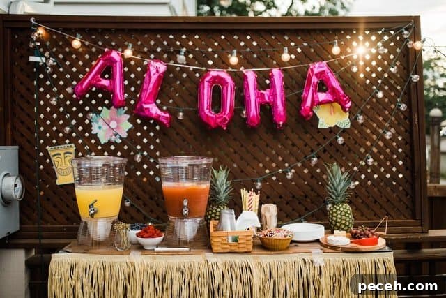 17 Fun and Memorable 13th Birthday Party Ideas 5 Tropical party theme table with "Aloha" backdrop and food and drinks on a table.