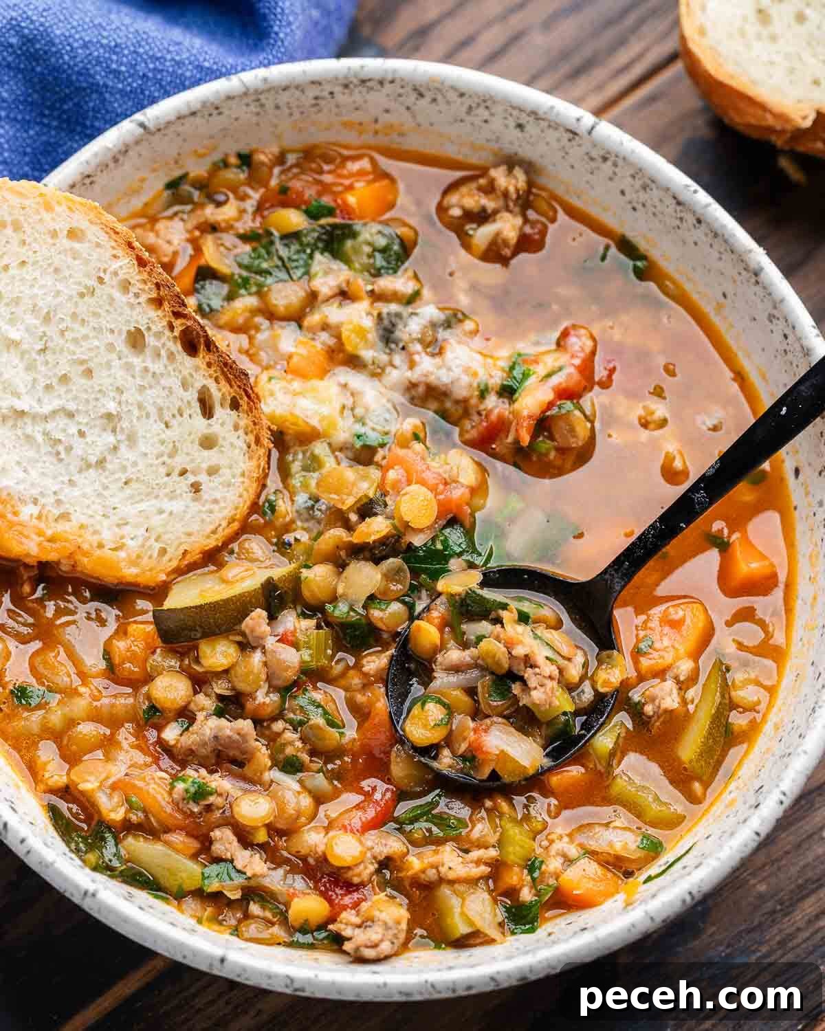 Hearty Sausage and Lentil Soup Recipe for Cozy Weeknights 2 Sausage lentil soup in white bowl with slice of bread.