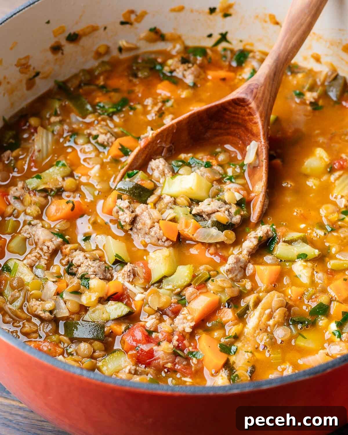 Hearty Sausage and Lentil Soup Recipe for Cozy Weeknights 4 Sausage lentil soup in large Dutch oven with wooden ladle.