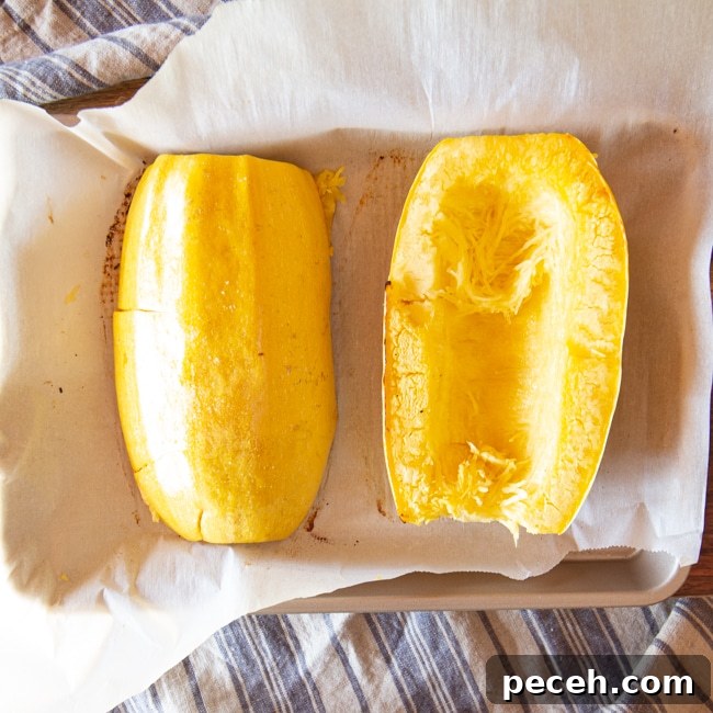 Two halves of a spaghetti squash just removed from the air fryer, with some strands pulled up.