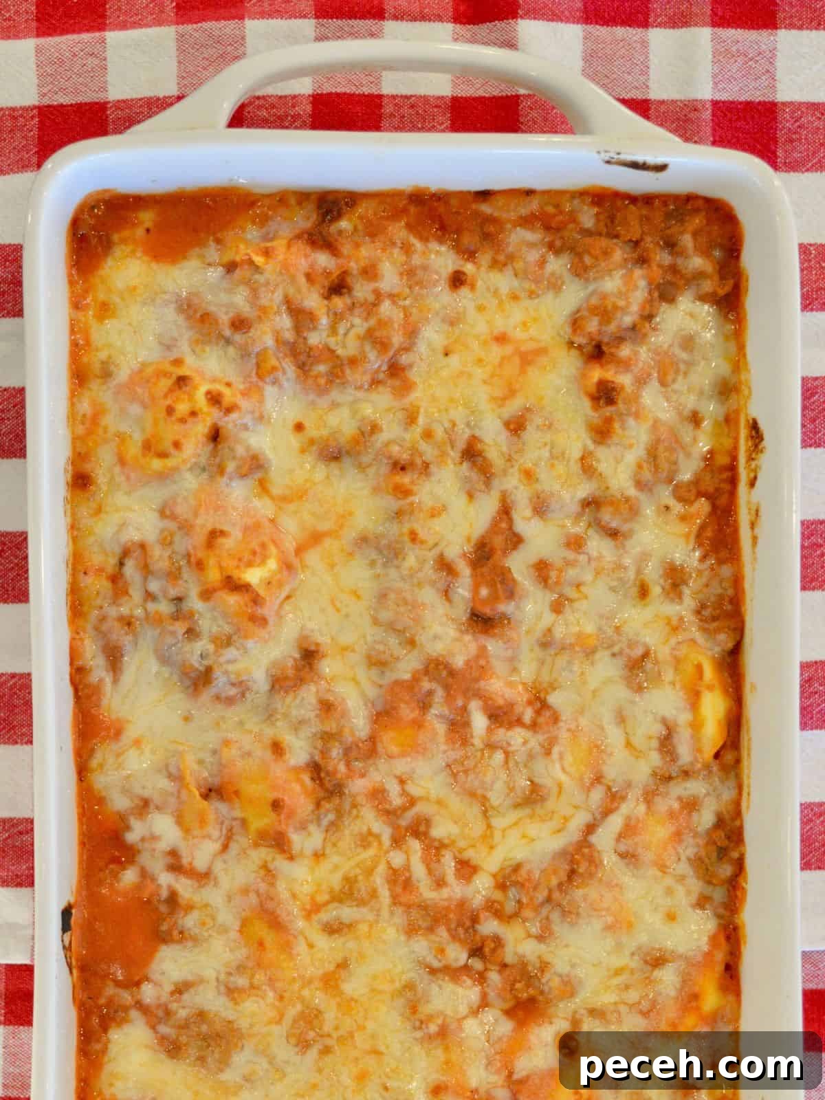 Cheesy Baked Tortellini Casserole with Rich Meat Sauce 2 Baked tortellini casserole with a ground turkey meat sauce and ricotta cheese in a white casserole dish.