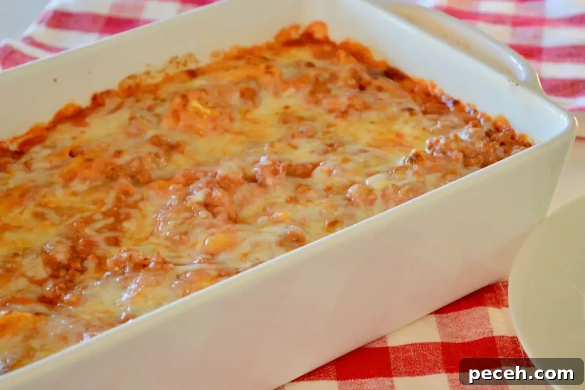 Cheesy Baked Tortellini Casserole with Rich Meat Sauce 4 Pasta bake in a white dish on a checkered napkin.