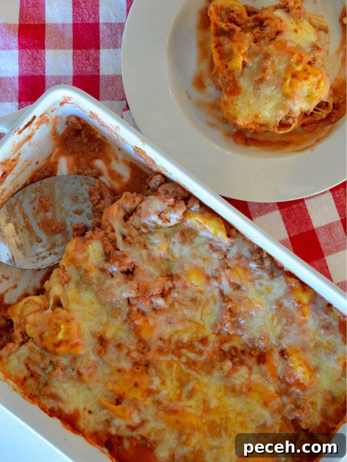 Cheesy Baked Tortellini Casserole with Rich Meat Sauce 5 Overhead photo of baked tortellini casserole in a white casserole dish with a bowl of pasta next to it.