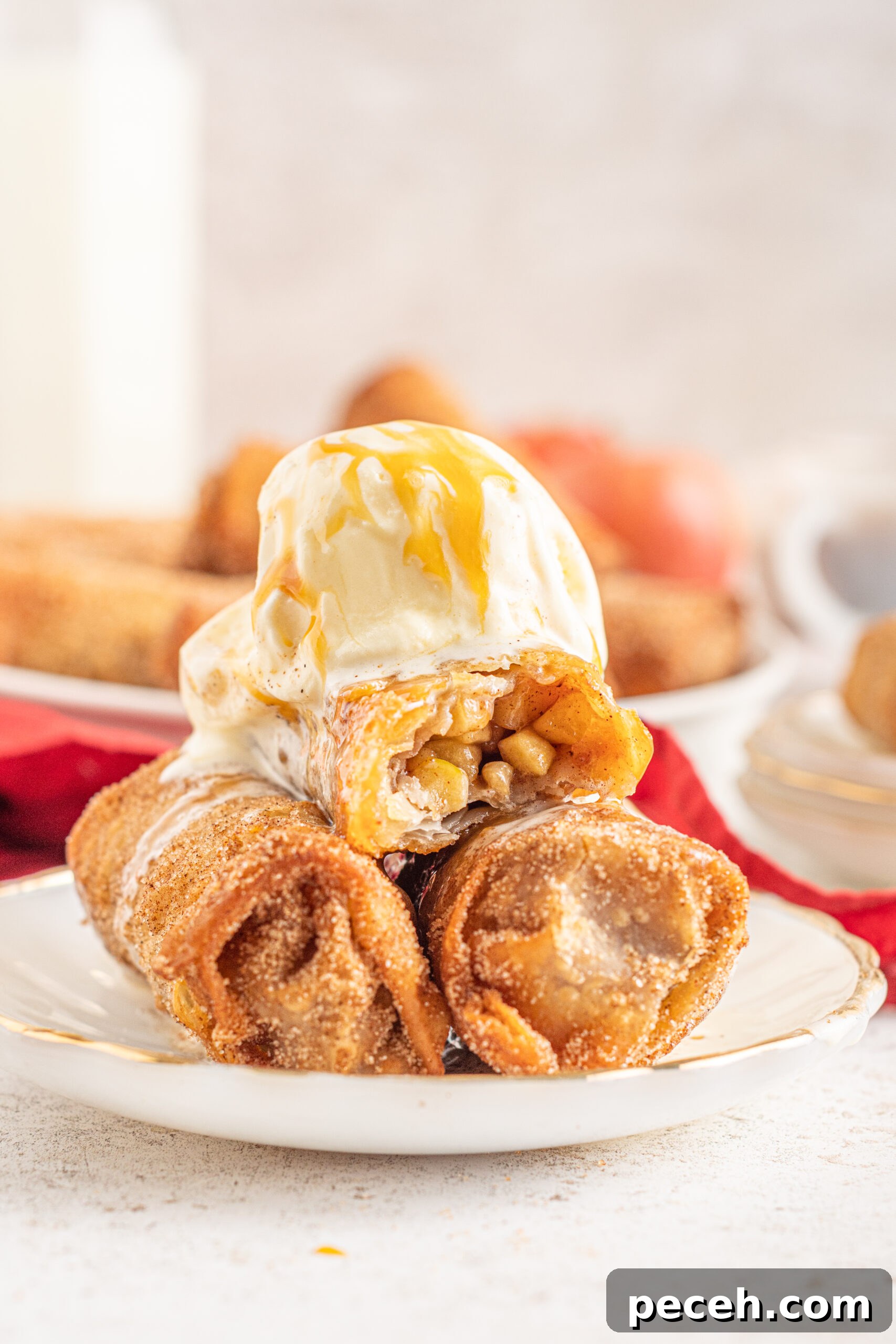 Crispy Apple Pie Egg Rolls with Cinnamon Sugar Dip 13 Three Apple Pie Egg Rolls stacked on a white plate with ice cream and caramel sauce on top.