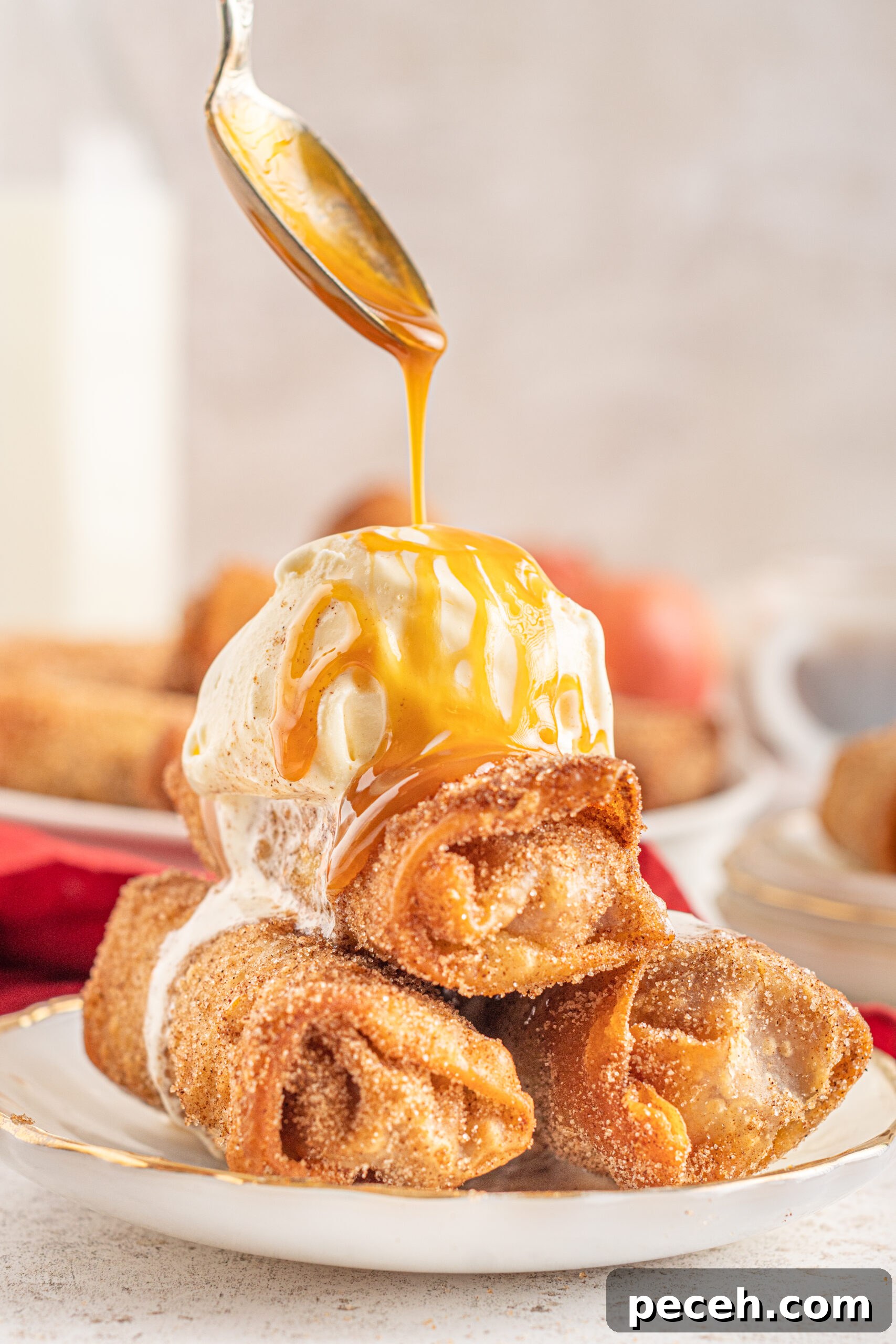 Crispy Apple Pie Egg Rolls with Cinnamon Sugar Dip 9 Three Egg Rolls stacked on a white plate with ice cream and caramel sauce on top.