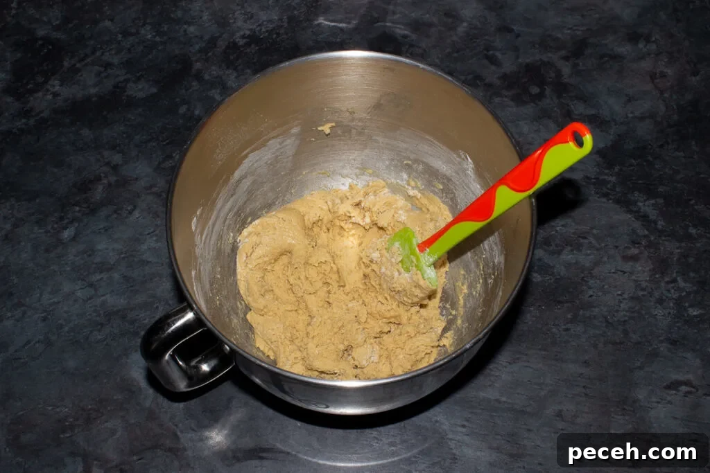 Crème Egg Cookie Recipe: Gooey Chocolate and Cadbury Filling 14 Cookie dough in the bowl of an electric stand mixer with a green spatula