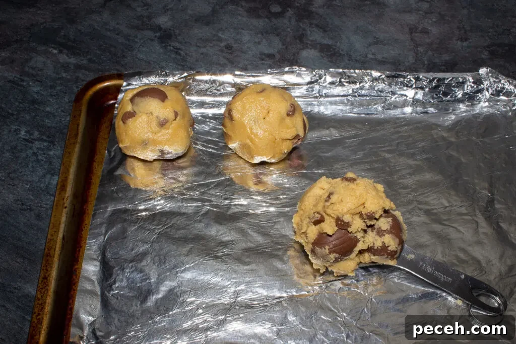 Crème Egg Cookie Recipe: Gooey Chocolate and Cadbury Filling 16 Creme Egg cookie dough being rolled into balls and put on a foil lined tray