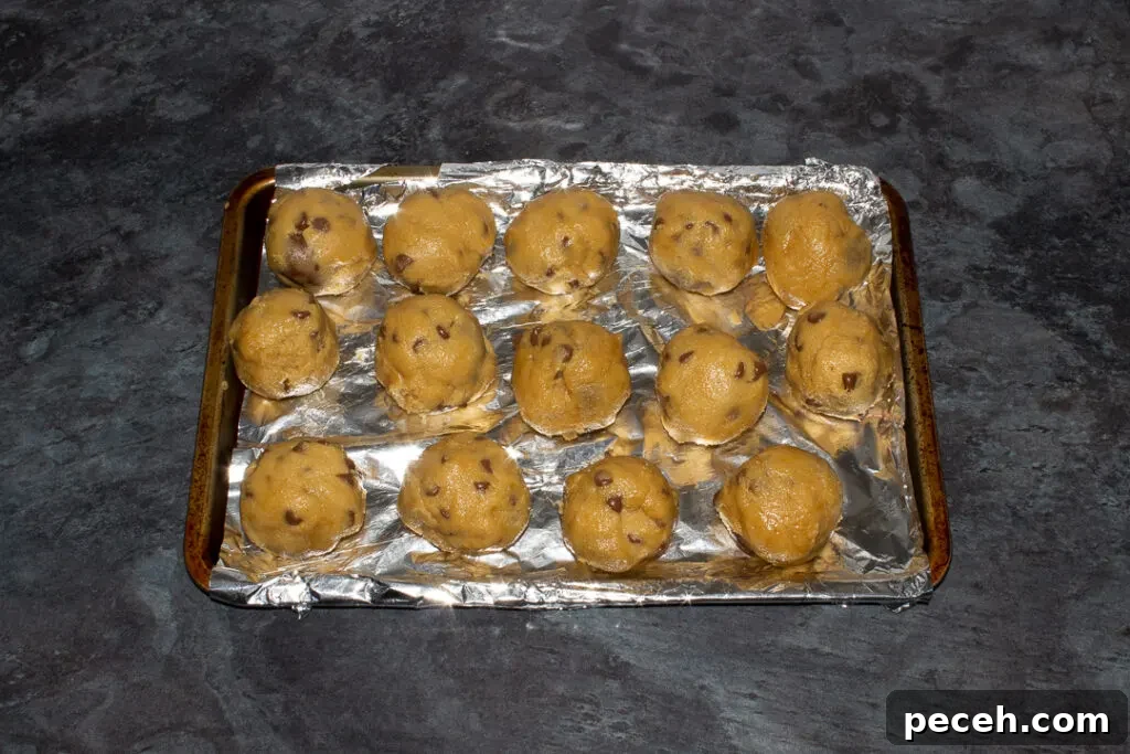 Crème Egg Cookie Recipe: Gooey Chocolate and Cadbury Filling 17 Creme Egg cookie balls on a foil lined baking tray