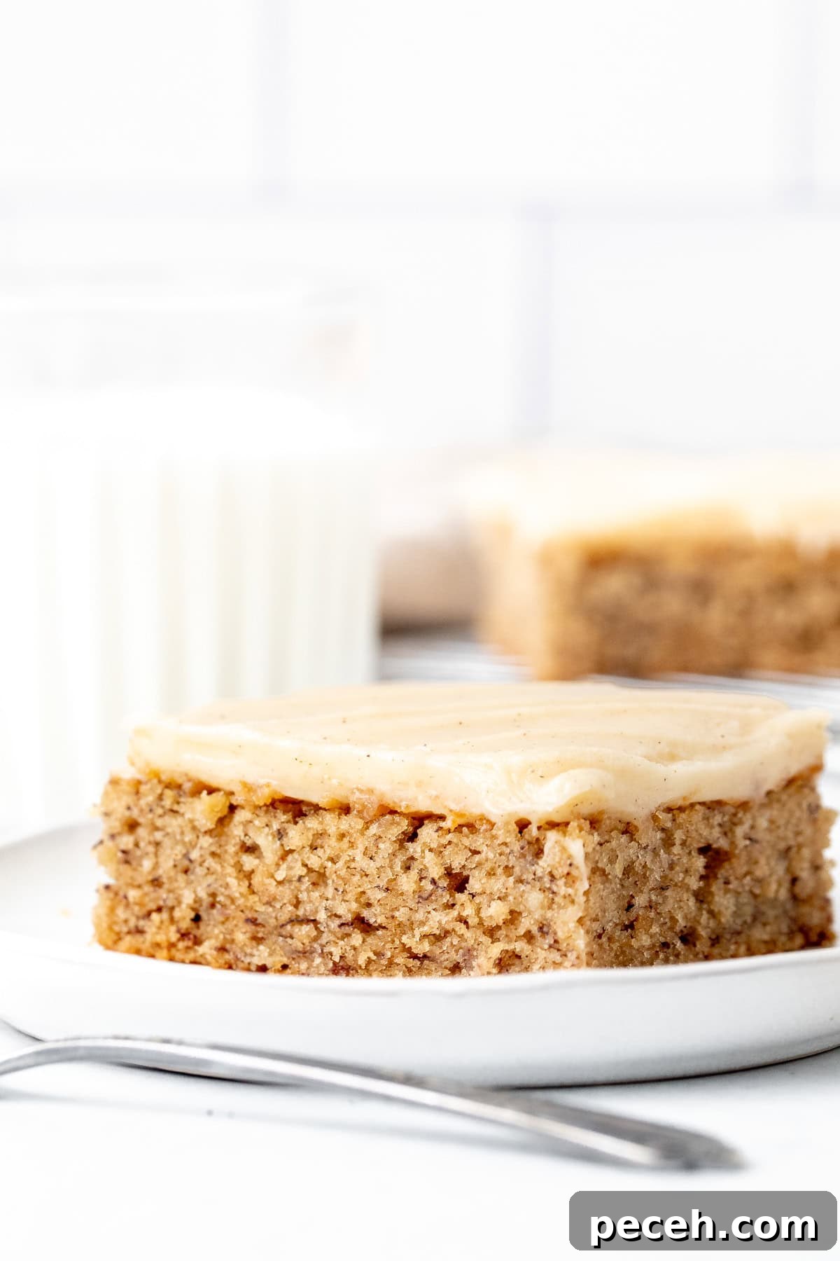 Moist Banana Bars with Cream Cheese Frosting Recipe 2 Banana bar with cream cheese frosting on a plate with glass of milk