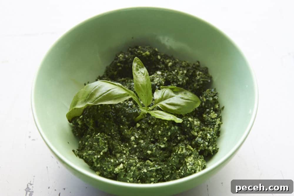 Kale and Walnut Pesto Recipe — Bright Sauce for Pasta & Toast 2 Kale pesto in a green bowl garnished with fresh basil.