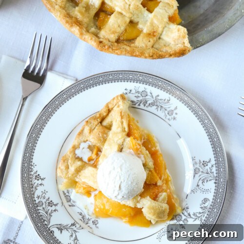 slice of peach pie on a piece of fine china with a fork on the side