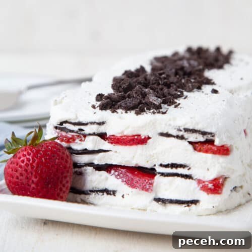 icebox cake with strawberries on a white platter with a whole strawberry.