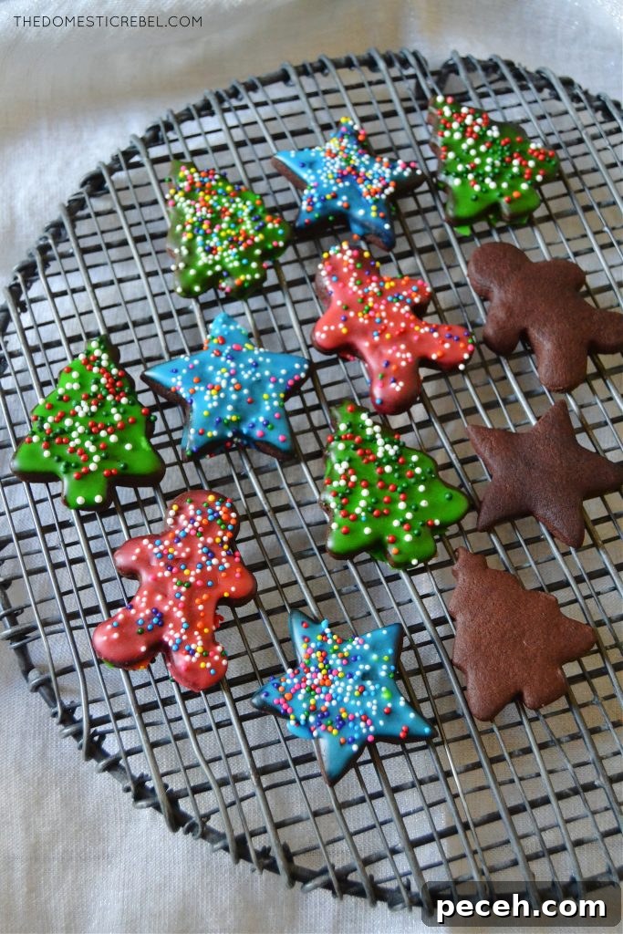No-Chill Chocolate Cut-Out Sugar Cookies — Crispy, Ready Fast 4 an assortment of chocolate sugar cookies, some frosted and some not, on a black wire rack