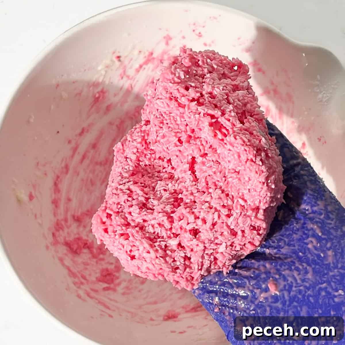 Coconut Ice Recipe: Creamy No-Bake Coconut Candy Tutorial 13 A hand holding the pink half of the coconut ice after it's been mixed.