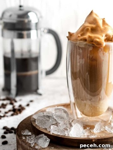 Iced coffee with condensed milk in a tall glass on a wooden plate