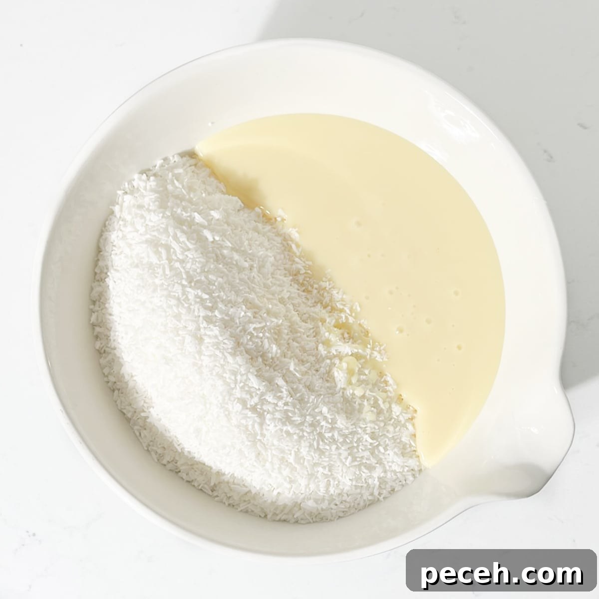 Coconut Ice Recipe: Creamy No-Bake Coconut Candy Tutorial 5 Coconut, icing sugar and condensed milk added to a large bowl.