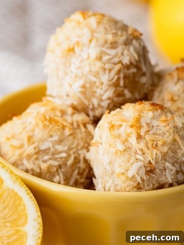 A bowl filled with coconut macaroons with a lemon wedge next to it.