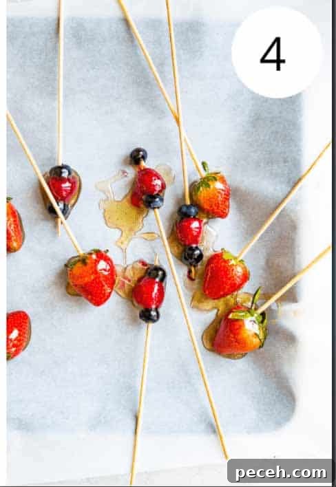 Tanghulu Candied Fruit Recipe — 3 Ingredients, Traditional Street Snack 5 Candied fruit on bamboo skewers on a pieces of parchment paper.
