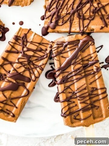 Chocolate fudgesicles drizzled in melted chocolate on a serving tray.