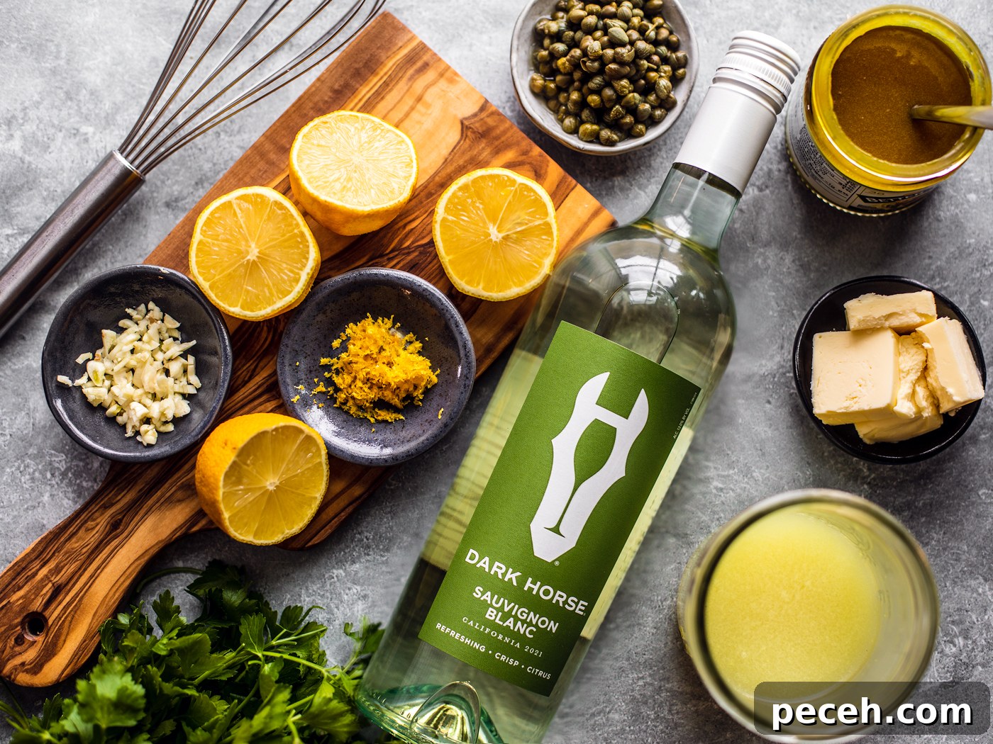 Classic Chicken Piccata Recipe with Lemon & Capers 3 Bottle of wine surrounded by lemons, fresh parsley, and small bowls of ingredients.