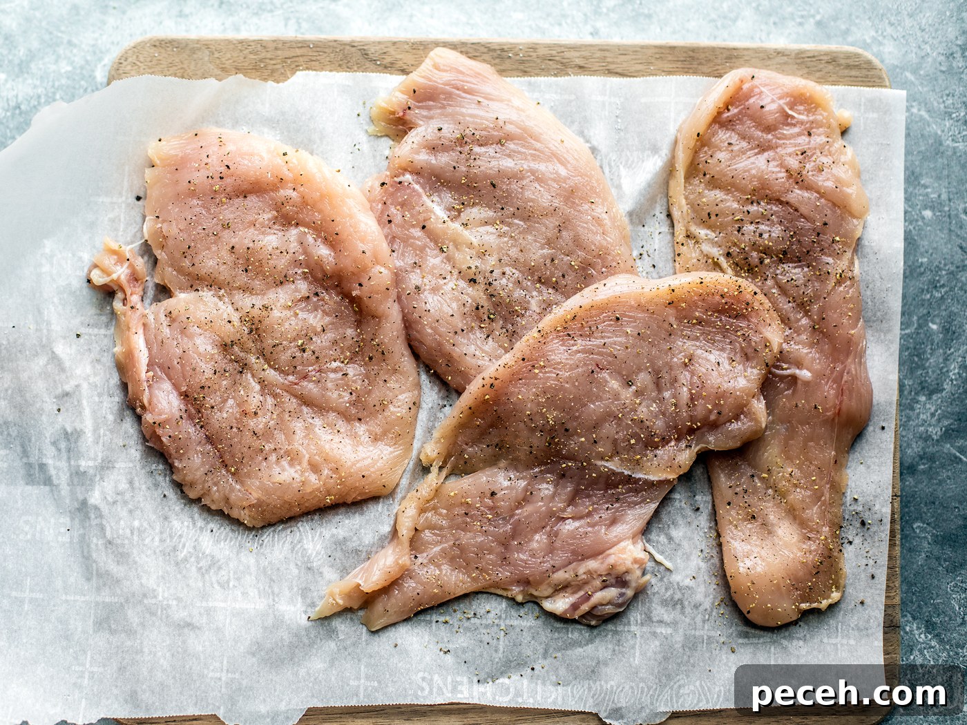 Classic Chicken Piccata Recipe with Lemon & Capers 4 Pounded out chicken cutlets on parchment-lined cutting board.