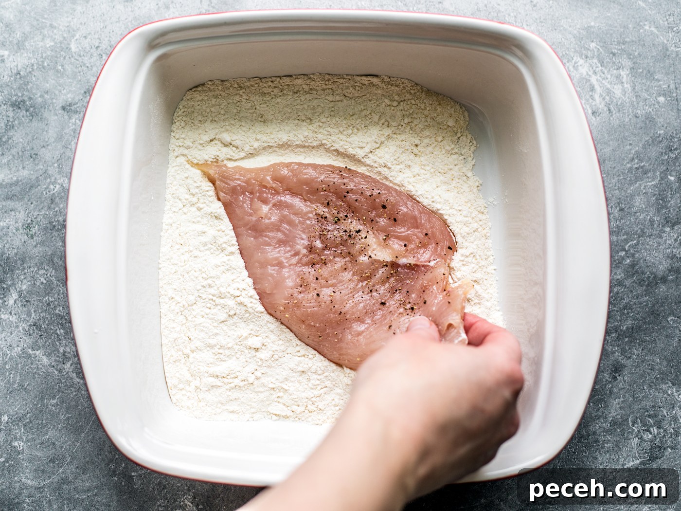 Classic Chicken Piccata Recipe with Lemon & Capers 5 Hand dredging chicken cutlet in flour.