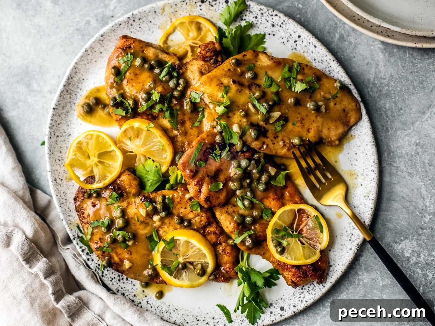 Classic Chicken Piccata Recipe with Lemon & Capers 8 Platter of chicken piccata smothered in sauce, capers, lemon slices, and fresh parsley.