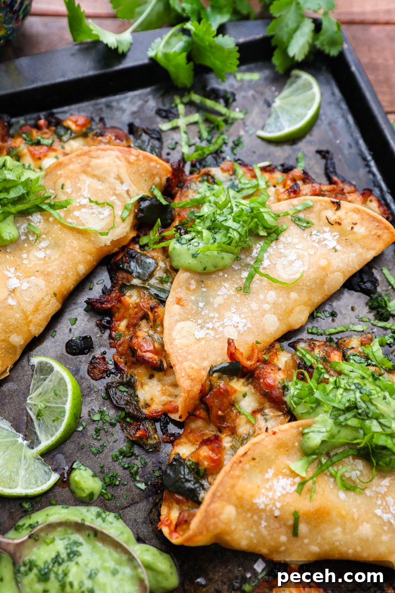 Crispy Poblano Chicken Tacos with Avocado Jalapeño Salsa 8 A cheesy crunchy baked chicken taco sitting on a large baking pan next to a spoonful of avocado-jalapeño salsa and fresh lime wedges