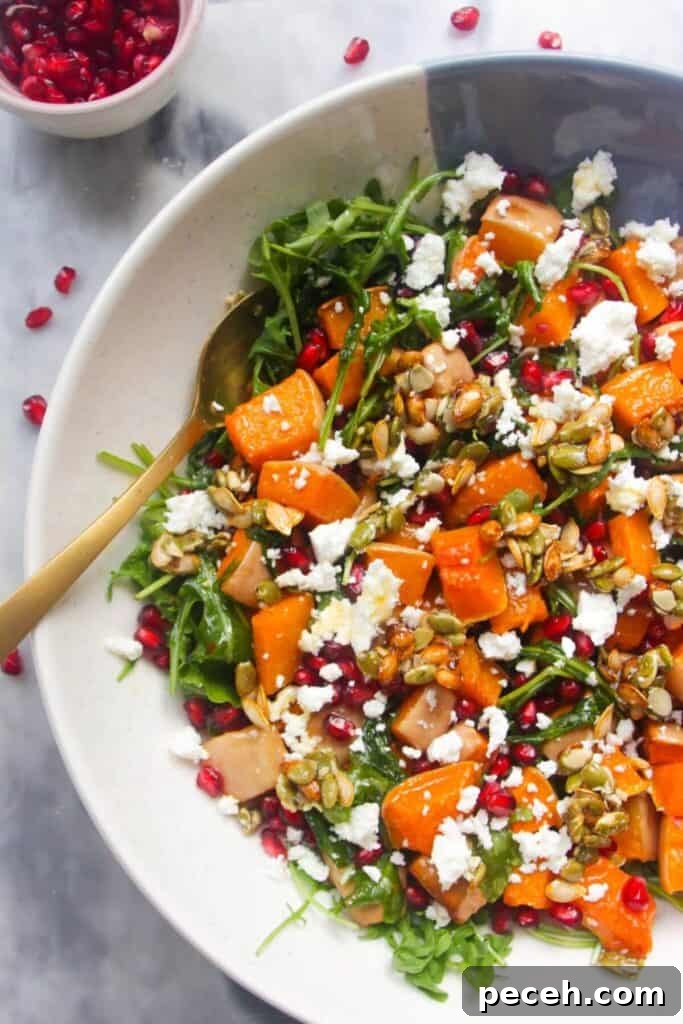 Cranberry-Dressed Crispy Rice Salad for Holiday Gatherings 13 Large white and blue serving bowl with colourful butternut squash salad inside and pomegranate seeds on the side.