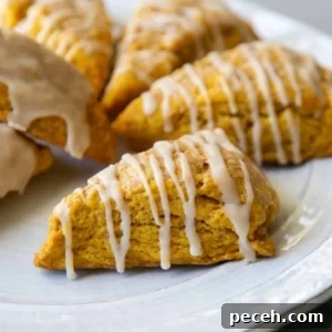 Maple-Glazed Pumpkin Scones Recipe for Fall Baking 16 close up of pumpkin scone with maple glaze on serving plate.