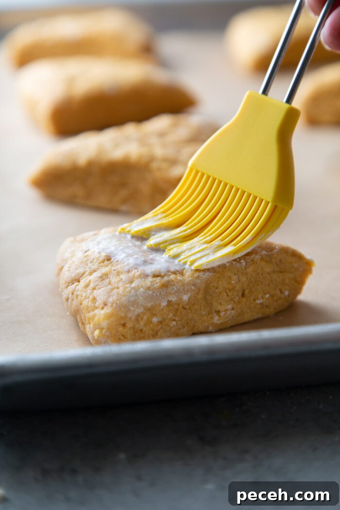 Maple-Glazed Pumpkin Scones Recipe for Fall Baking 9 brush scone wedges with heavy cream before baking.