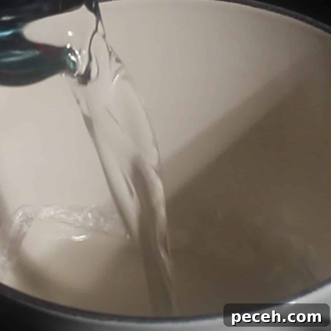 Water being poured into a saucepan to start pumpkin cold foam syrup recipe.