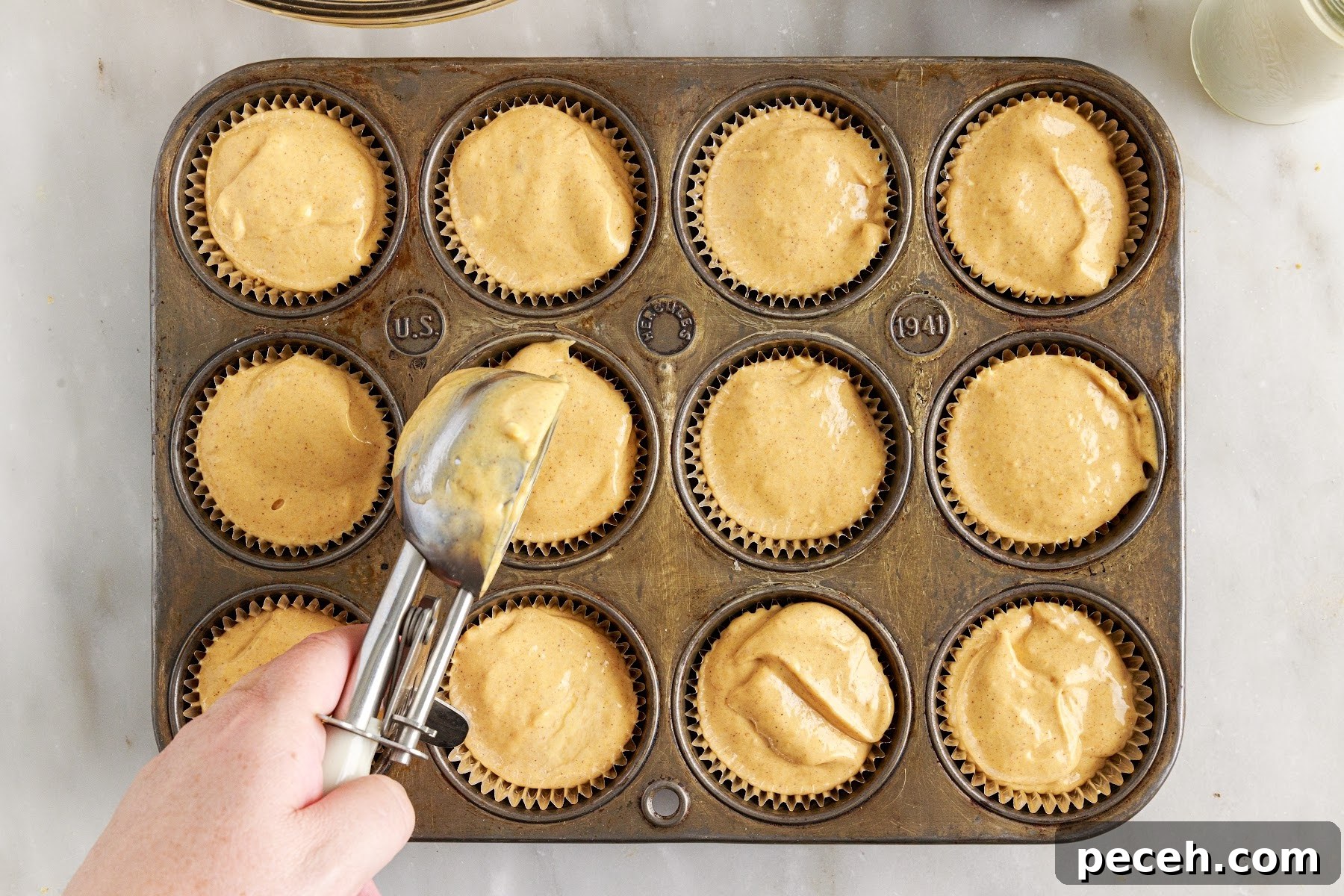 Scooping pumpkin cheesecake mixture into muffin tins.