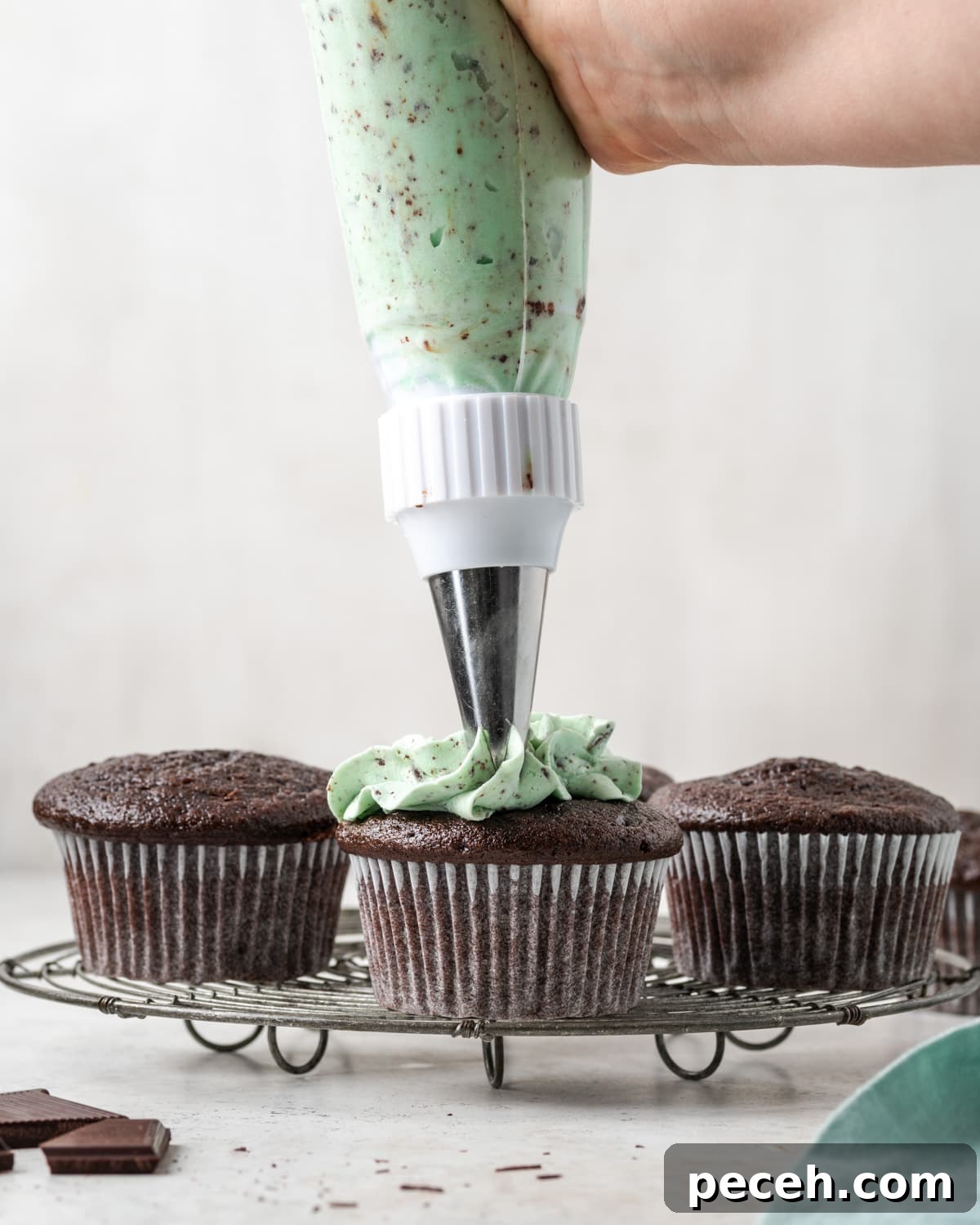 Mint Chocolate Chip Frosting Recipe for Smooth, Creamy Results 10 Mint chocolate chip frosting being piped onto a chocolate cupcake.