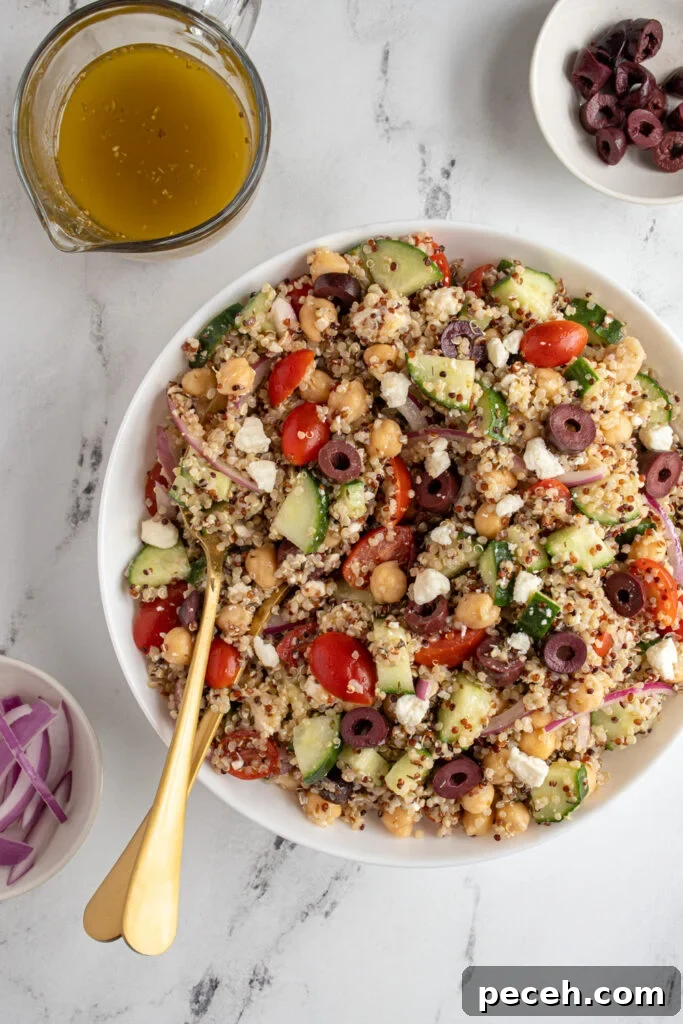 Greek Quinoa and Chickpea Salad with Feta and Olives 3 Overhead of a white bowl with greek quinoa chickpea salad with serving spoons.