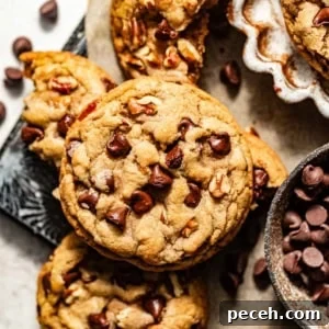 Chewy Banana Chocolate Chip Cookies Recipe for Perfect Bakes 15 banana chocolate chip cookies on a piece of parchment paper with chocolate chips sprinkled around them.