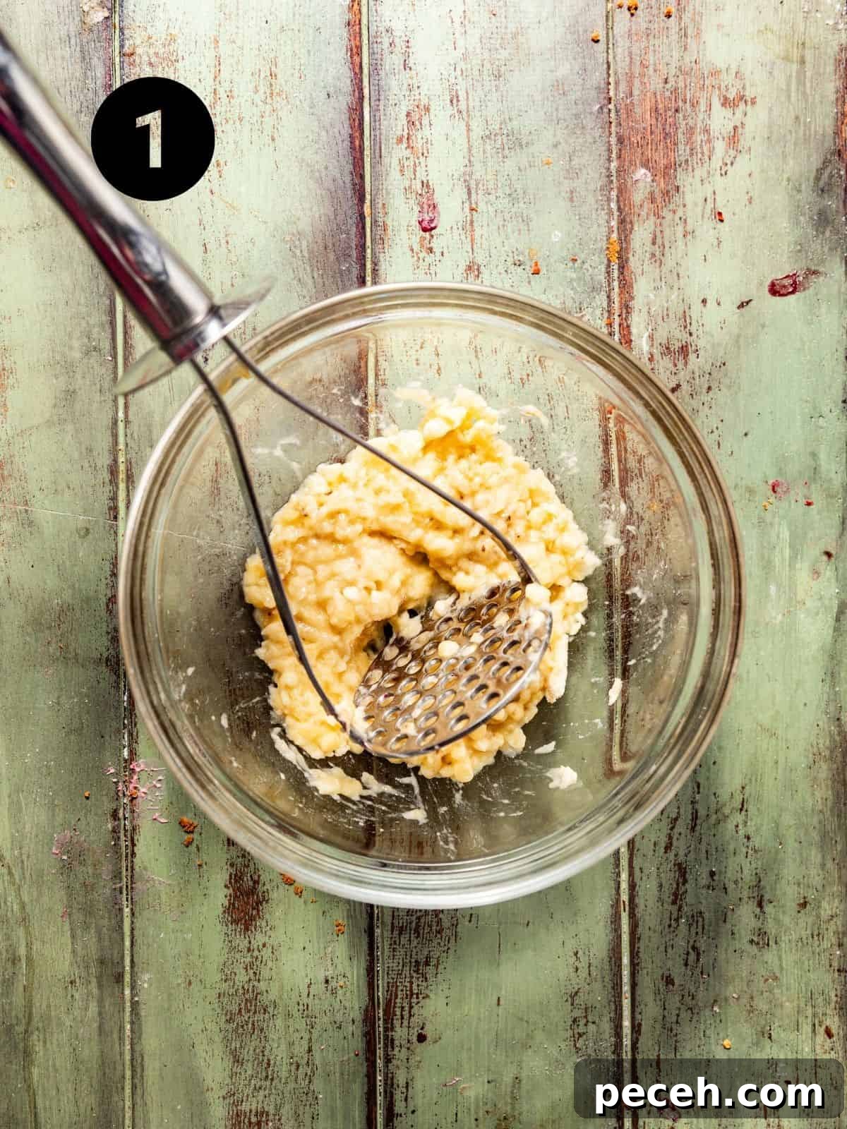 Chewy Banana Chocolate Chip Cookies Recipe for Perfect Bakes 4 mashed bananas in a bowl with a potato masher.