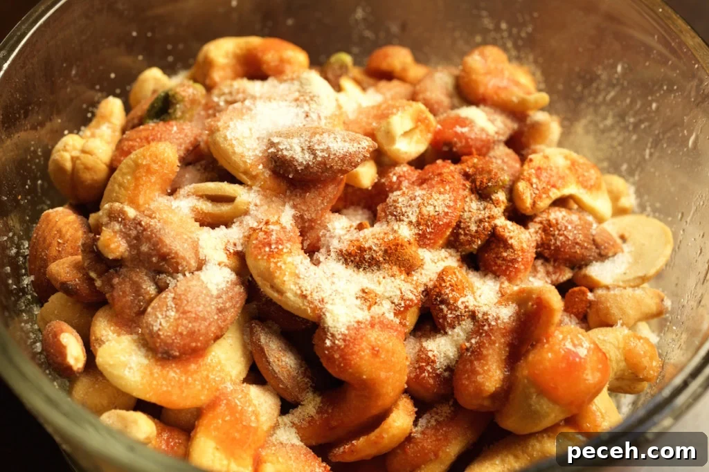 Crispy Buffalo-Spiced Nuts Recipe for Game Day Snacks 3 Mixed nuts in a glass bowl covered in spices, salt, and hot sauce - the ingredients for buffalo spiced nuts.